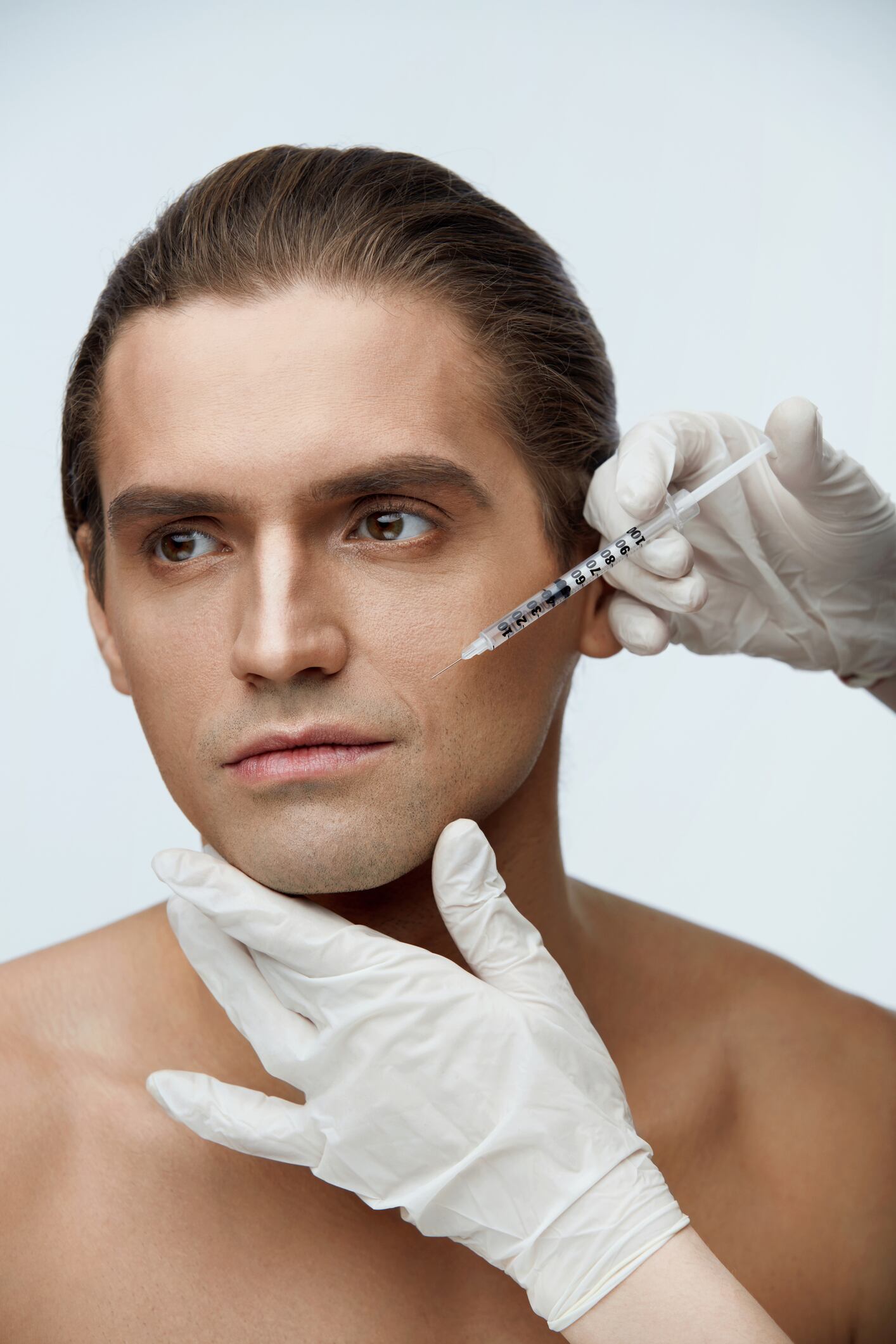 Face Procedure. Portrait Of Handsome Young Man Receiving Facial Lifting Injections. Closeup Of Beautician Hands Doing Cosmetic Injection On Male Cheekbone. Beauty Treatment Concept. High Resolution