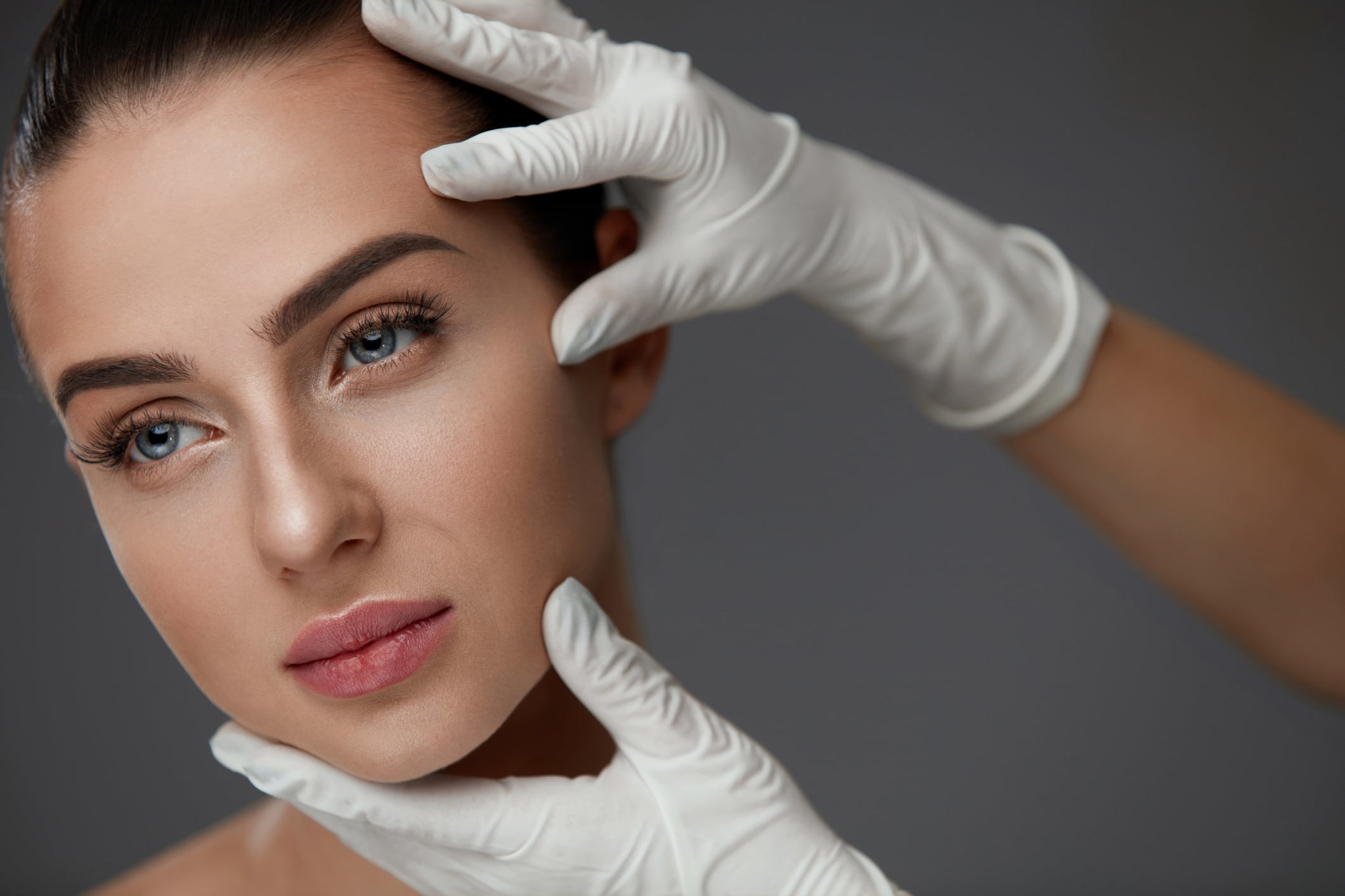 Beauty Woman Face. Portrait Beautiful Girl With Perfect Makeup And Smooth Soft Healthy Skin. Closeup Of Cosmetician Hands In Gloves Touching Young Woman Facial Skin. Plastic Surgery. High Resolution