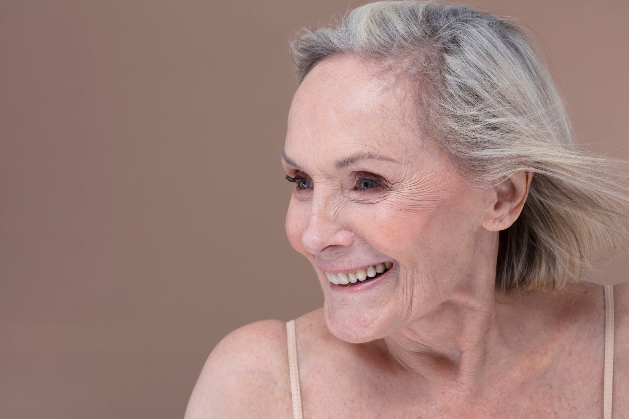 Studio shot of smiling senior woman with windswept hair