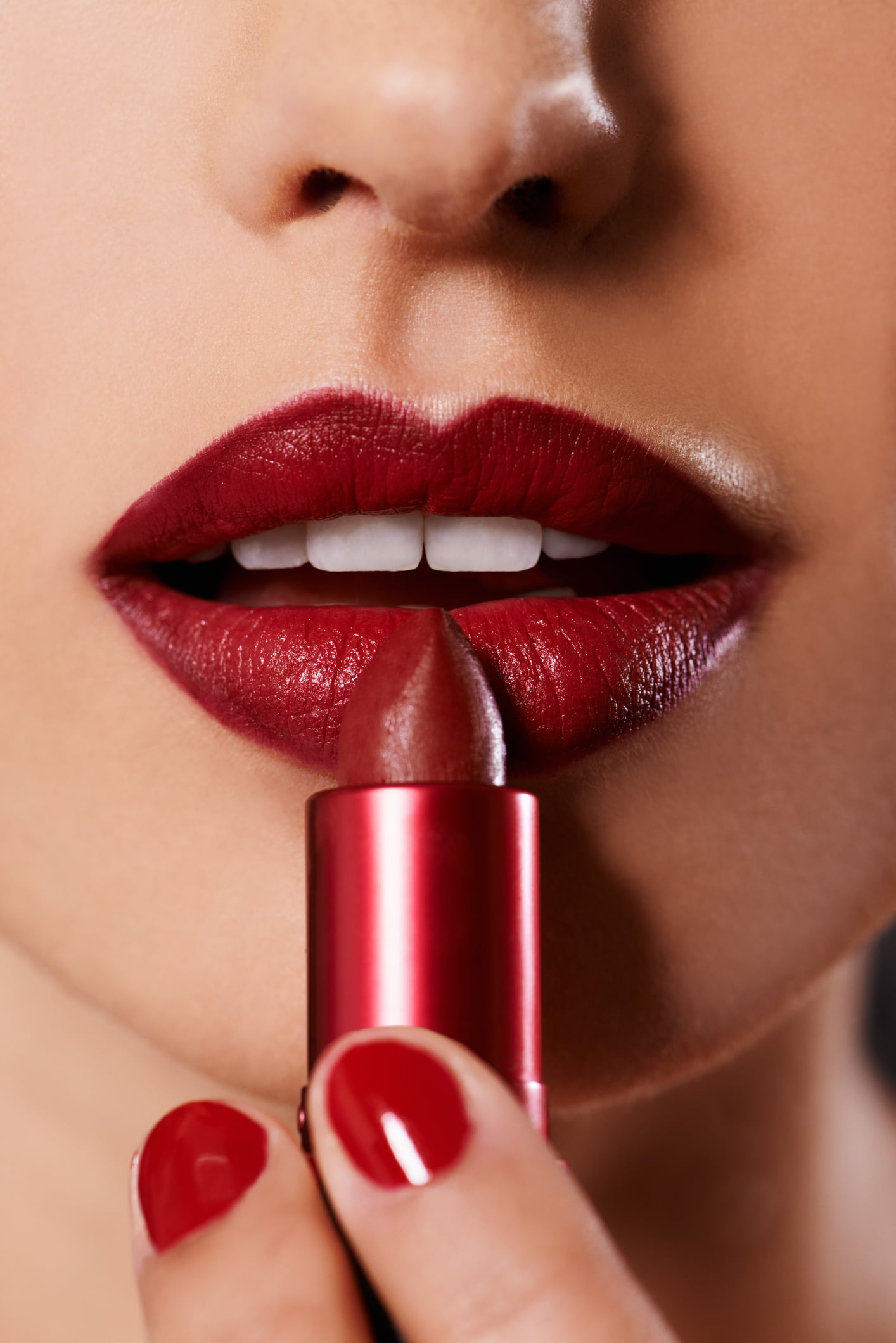 Closeup image of a woman applying lipstick