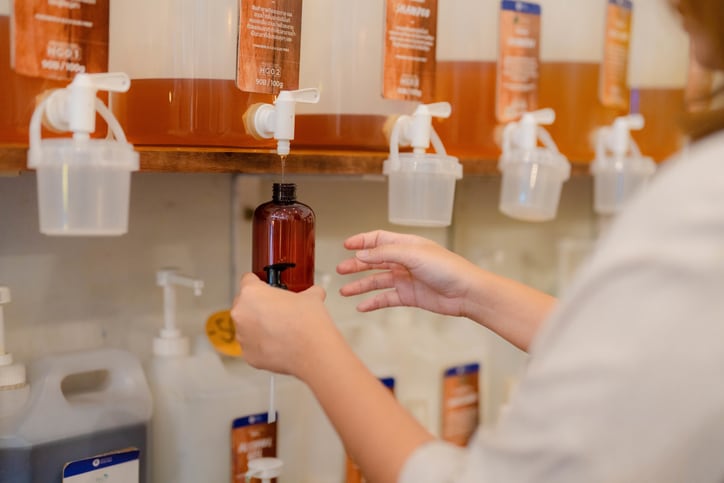 Woman filling container with beauty product in plastic free store