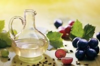 Grape seed oil in a glass jug with seeds, fruit and leaves.